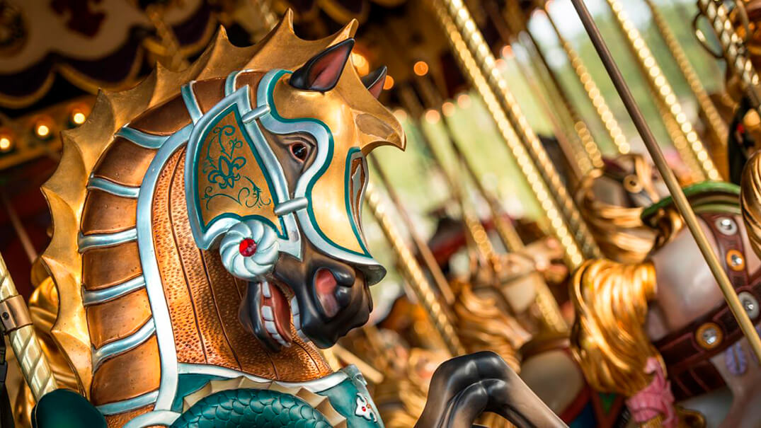 Coloridos caballos del carrusel girando en Le Carrousel de Lancelot, una atracción clásica en Disneyland Paris.